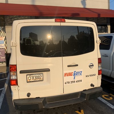 HVAC Guyz & Plumbing Inc — rear of a branded HVAC Guyz Nissan NV1500 service van with logo and phone 470-255-4535