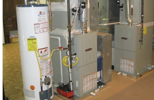 HVAC Guyz & Plumbing Inc — two gas furnaces and a Rheem water heater lined up in a residential mechanical room